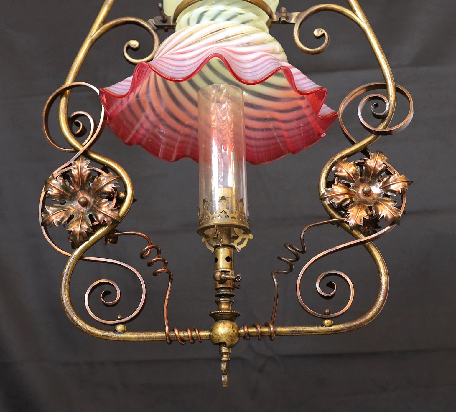 An English Arts & Crafts lacquered brass and copper gasolier with red tinted Vaseline glass shade, height 80cm. width 40cm